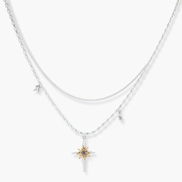 Two-layer silver-toned necklace with star charms and dagger pendant featuring golden sun motif on white background.