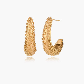 Curved gold hoop earrings with raised granulated texture resembling sea urchin surface on cream background