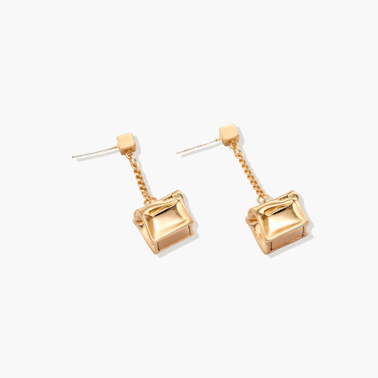Modern geometric jewelry set featuring crumpled cube pendants in warm gold finish with chain details on beige background.