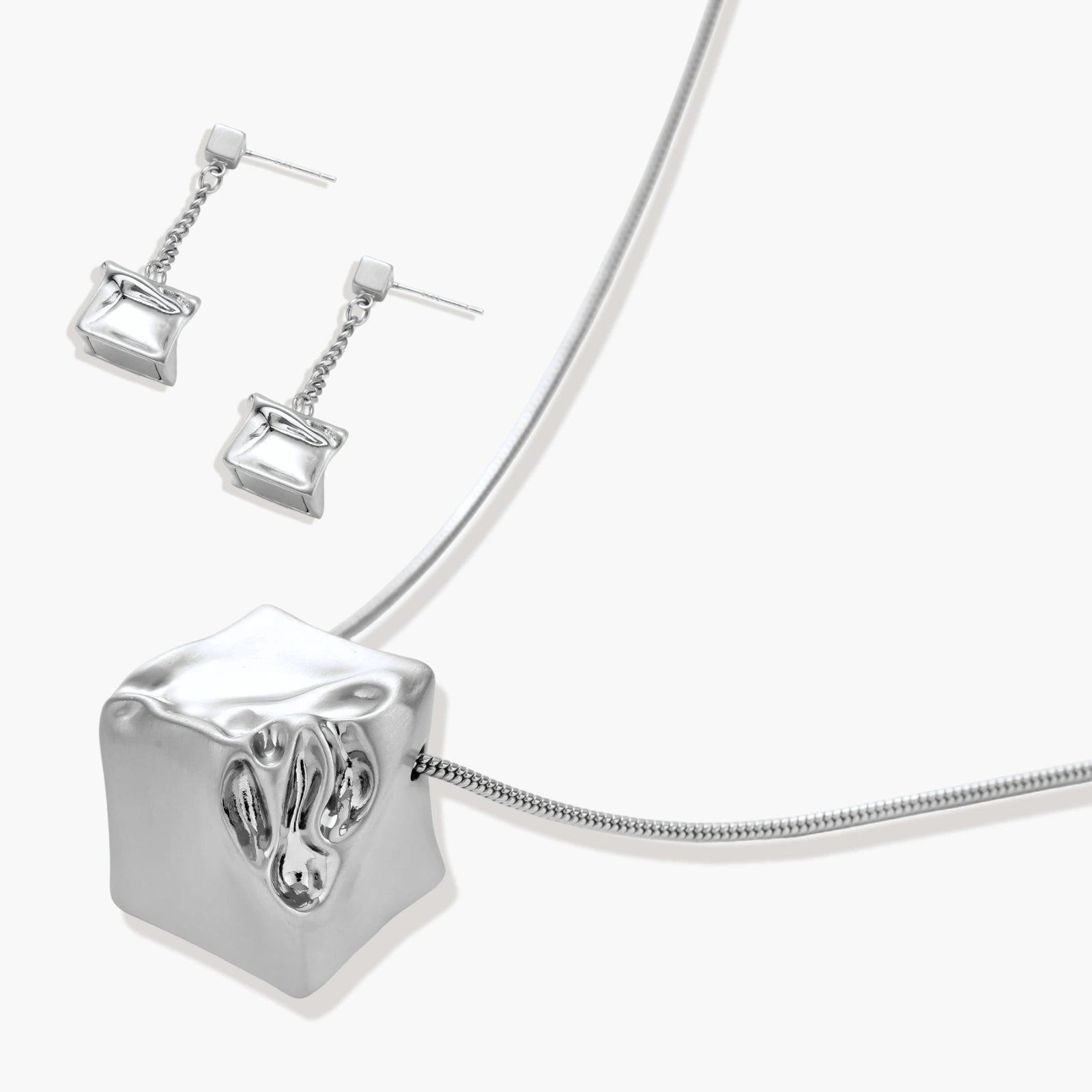 Geometric jewelry set with textured cube pendants on chains, featuring eco-zinc alloy in silver and gold finishes.