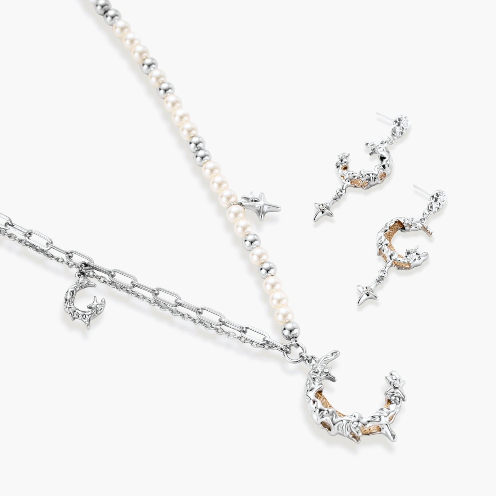 Mixed-metal jewelry set featuring layered necklaces with crescent moon pendant and pearl beads, plus matching star-drop earrings.