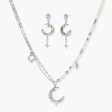 Mixed-metal jewelry set featuring layered necklaces with crescent moon pendant and pearl beads, plus matching star-drop earrings.