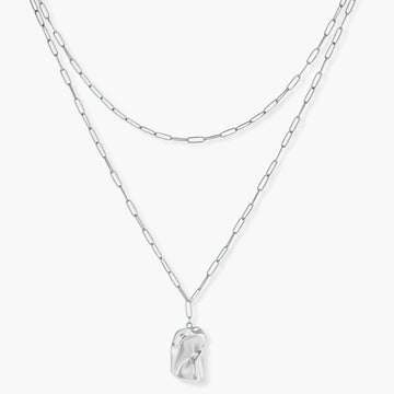 Silver layered necklace with organic flowing pendant in eco-zinc alloy on neutral background, showing adjustable chain design.
