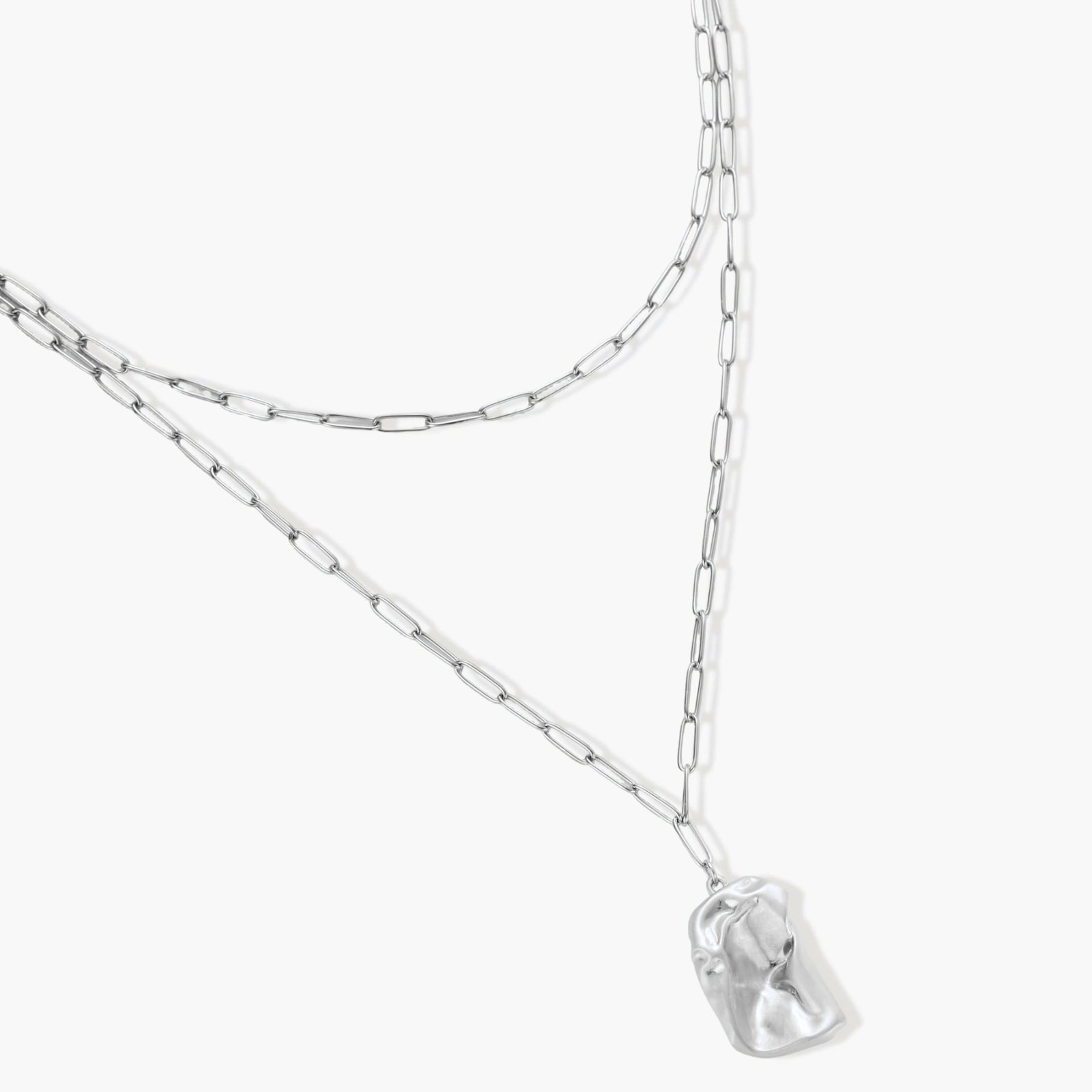 Silver layered necklace with organic flowing pendant in eco-zinc alloy on neutral background, showing adjustable chain design.
