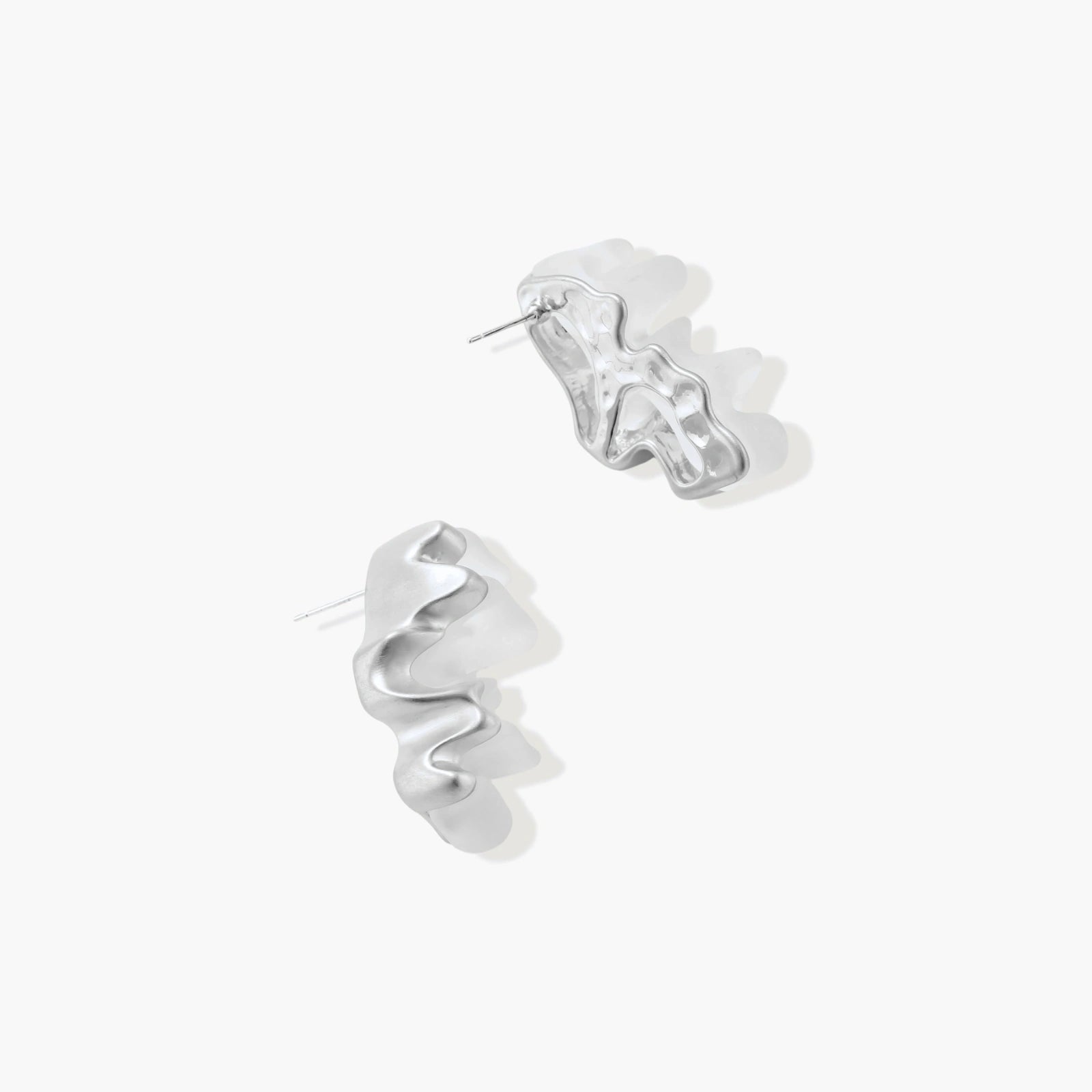 Pair of silver-toned sculptural earrings with flowing abstract forms and stud backs against white background.