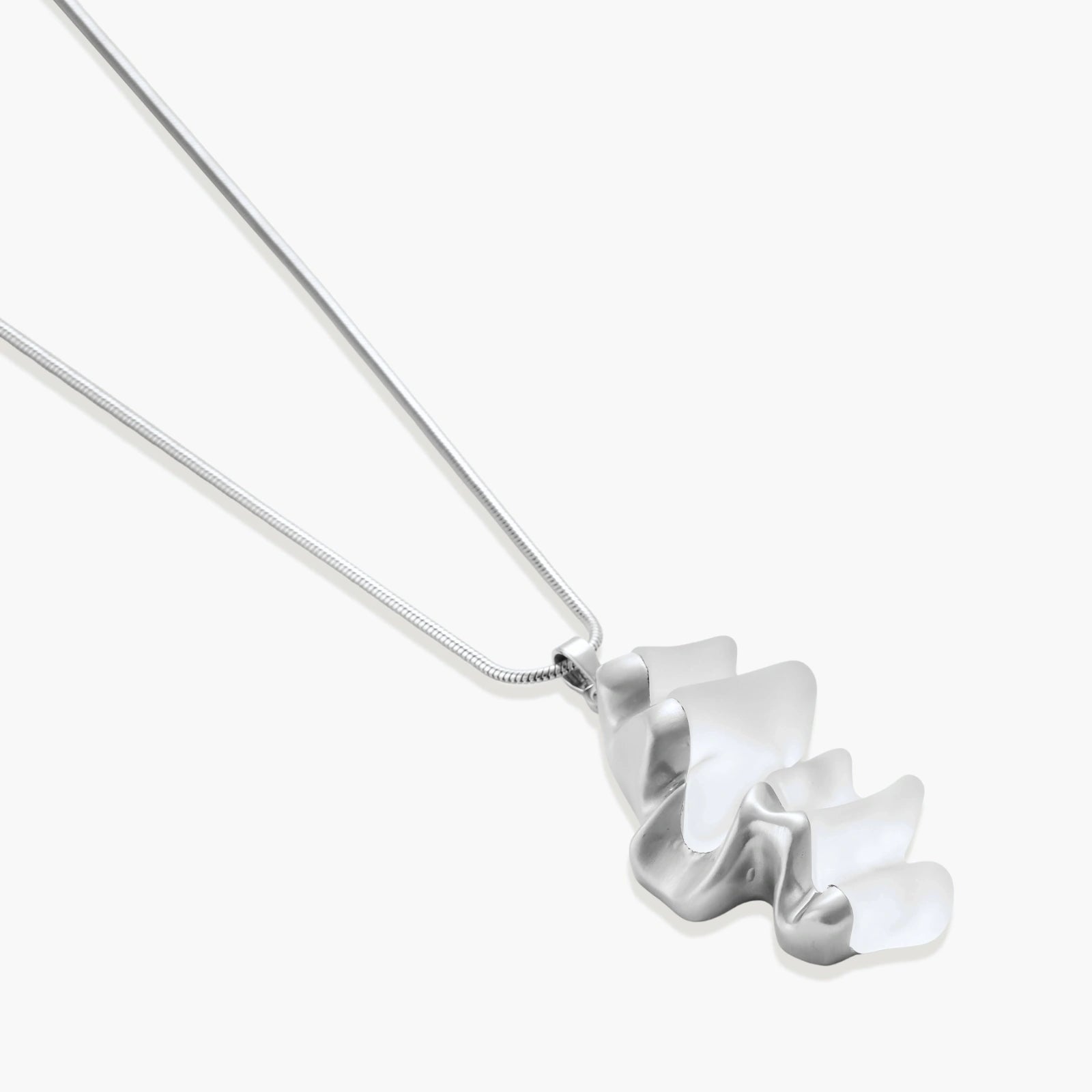 Modern sculptural pendant necklace with twisted metallic design on delicate silver chain against neutral background.
